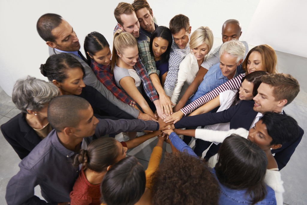 Shot of a diverse group of business people joining their hands in a symbol of unity